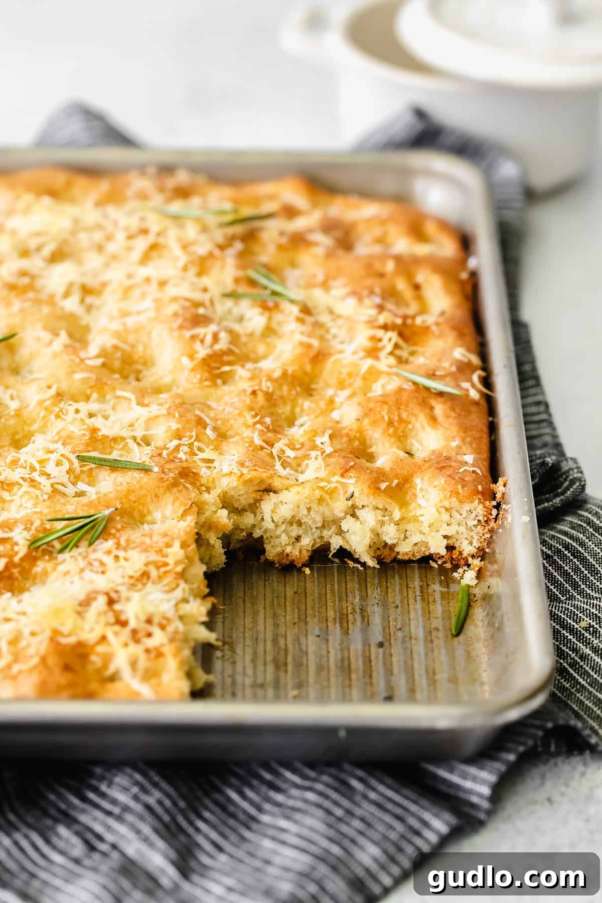 Whole Focaccia Loaf Ready to Serve A large, golden Parmesan Rosemary Focaccia bread in a baking pan, ready to be sliced and served, showcasing its rustic beauty