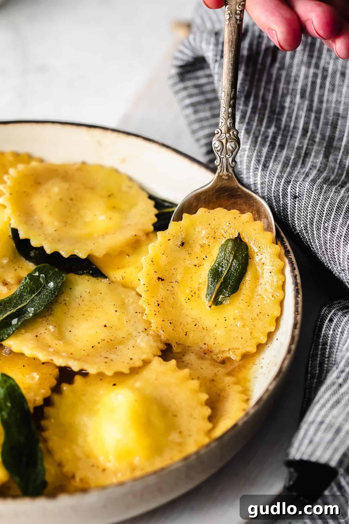 Goat Cheese Ravioli on a Spoon A single piece of homemade goat cheese ravioli held on a spoon, showcasing its perfect shape and filling.