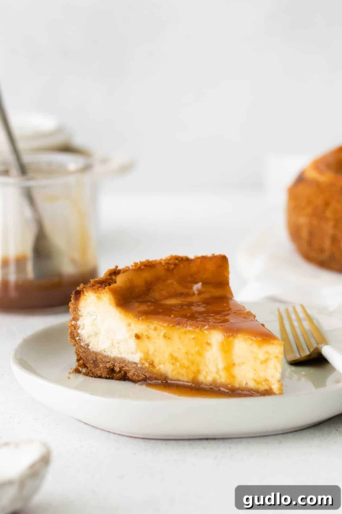Salted Caramel Cheesecake Perfection 2 A perfectly sliced piece of baked salted caramel cheesecake, showcasing its creamy texture and a generous drizzle of homemade salted caramel topping.