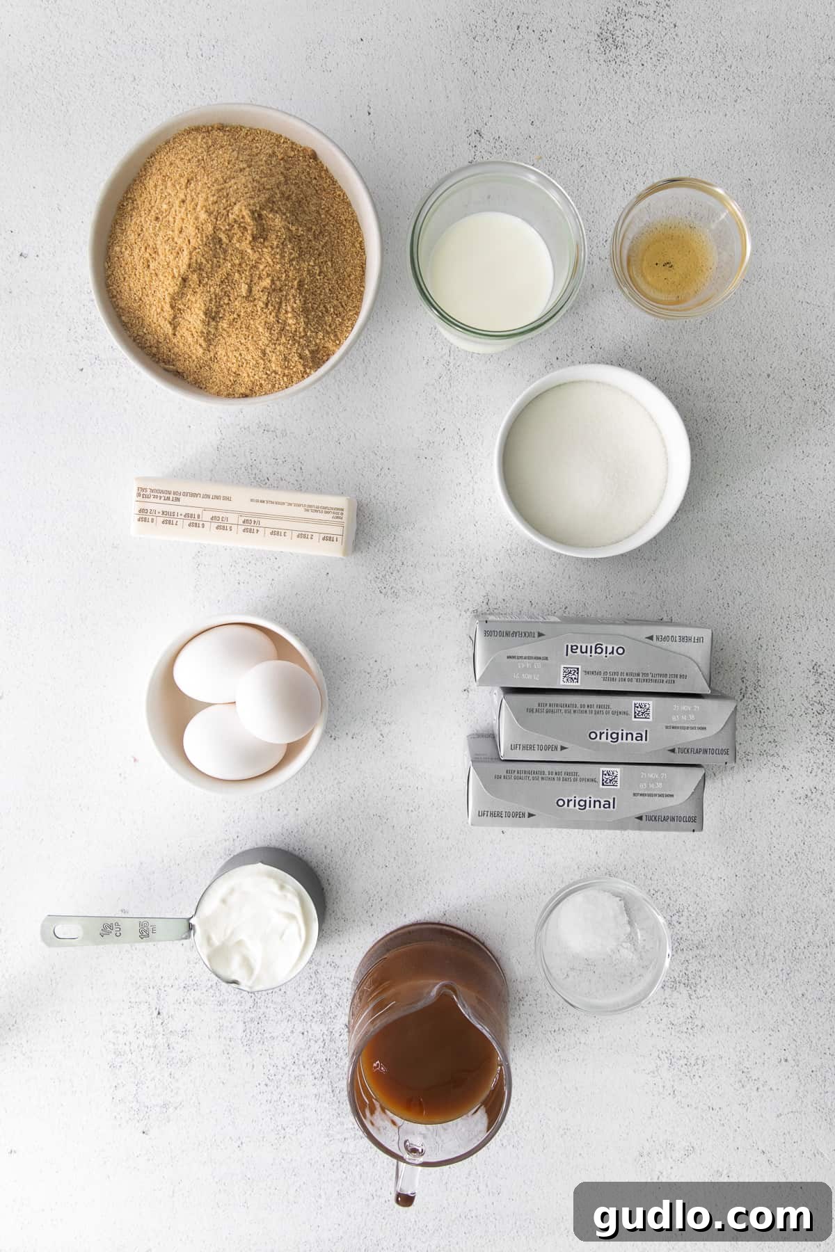 Salted Caramel Cheesecake Perfection 3 Bowls filled with all the ingredients required for baking a salted caramel cheesecake, arranged neatly on a kitchen counter.
