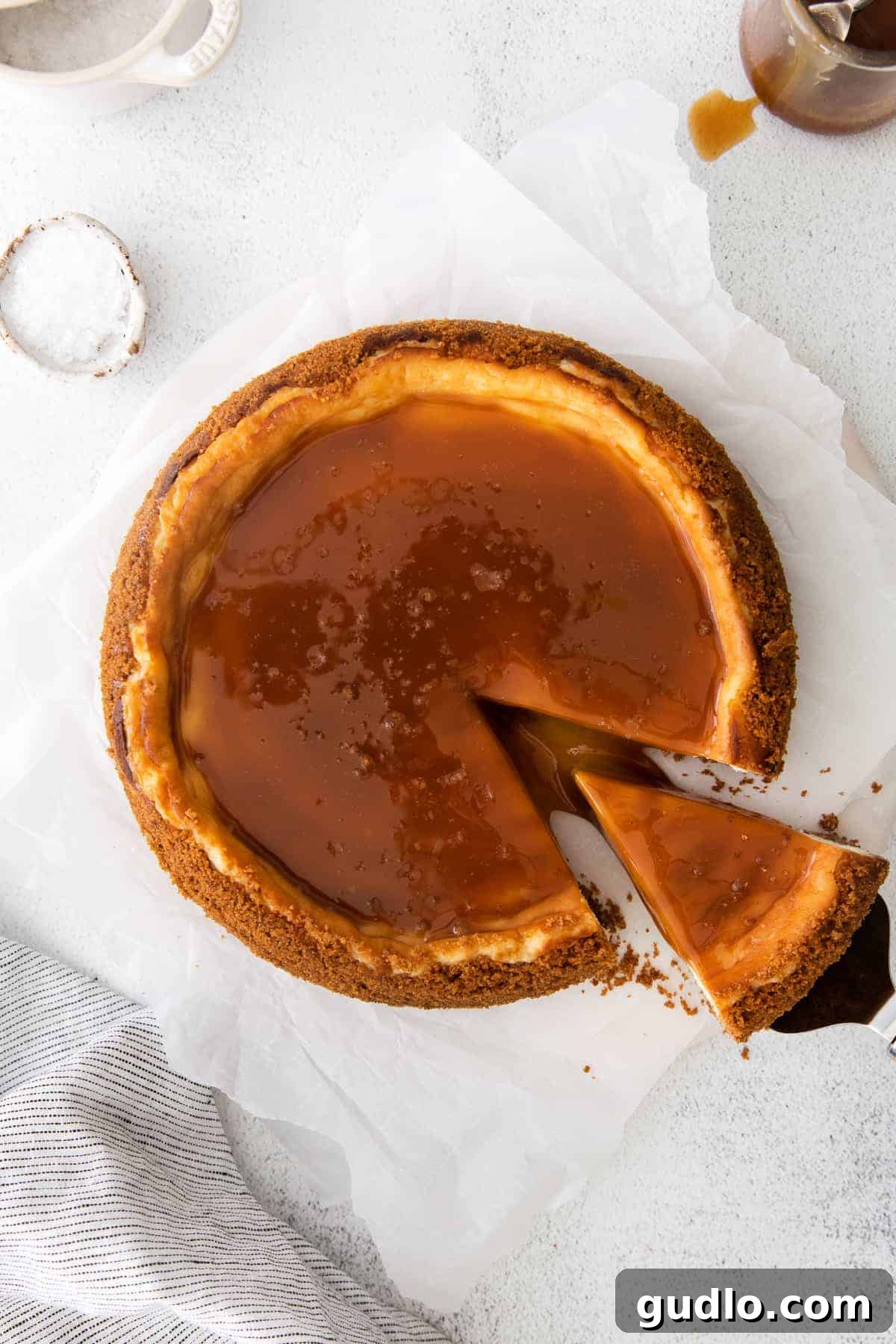 Salted Caramel Cheesecake Perfection 9 A hand cutting into a gloriously drizzled salted caramel cheesecake, showcasing its perfect slices.