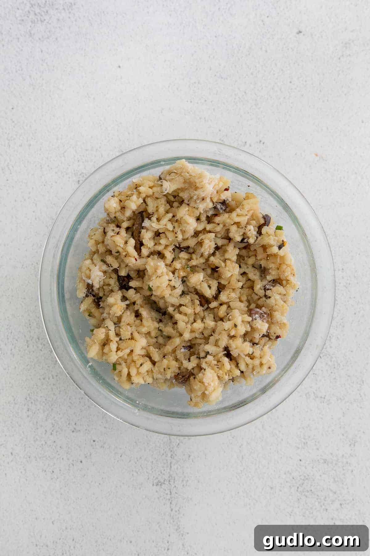 Got leftover risotto? Make Parmesan Arancini - a delicious fried rice ball appetizer! A bowl filled with perfectly cooked and cooled risotto, ready for transformation into arancini.
