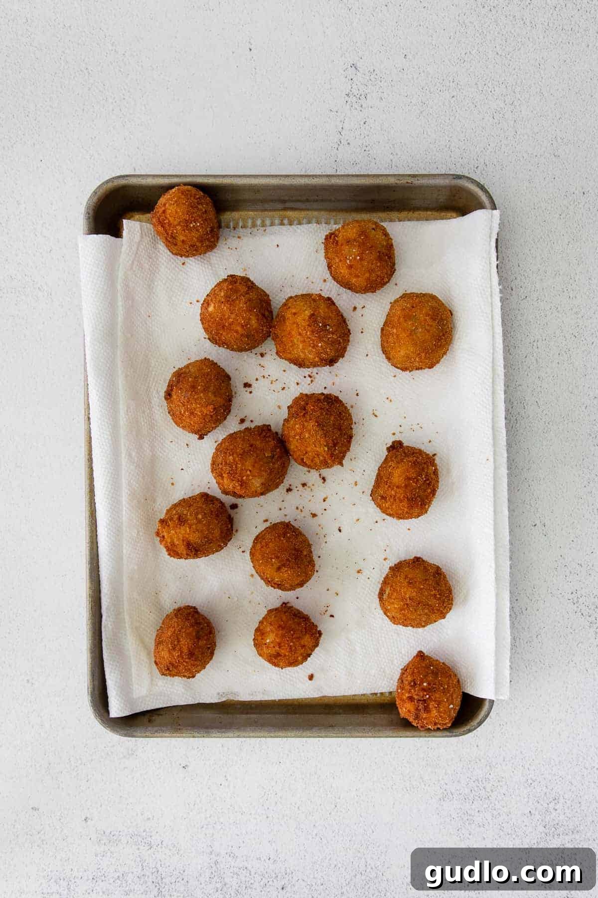 Make these delicious arancini balls with cooked risotto (arborio rice), parmesan cheese, breadcrumbs, and oil. A close-up view of golden, crispy fried arancini balls, ready to be enjoyed.