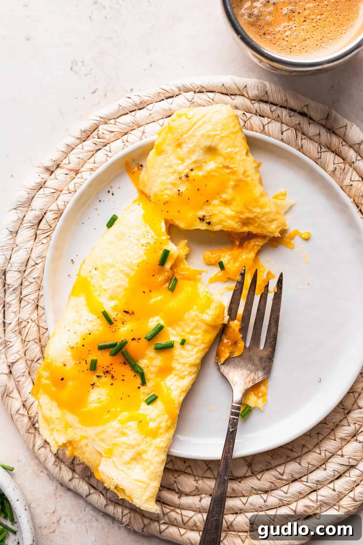 A perfectly cooked, golden cheese omelette served on a white plate with a fork, ready to be enjoyed for breakfast or brunch.