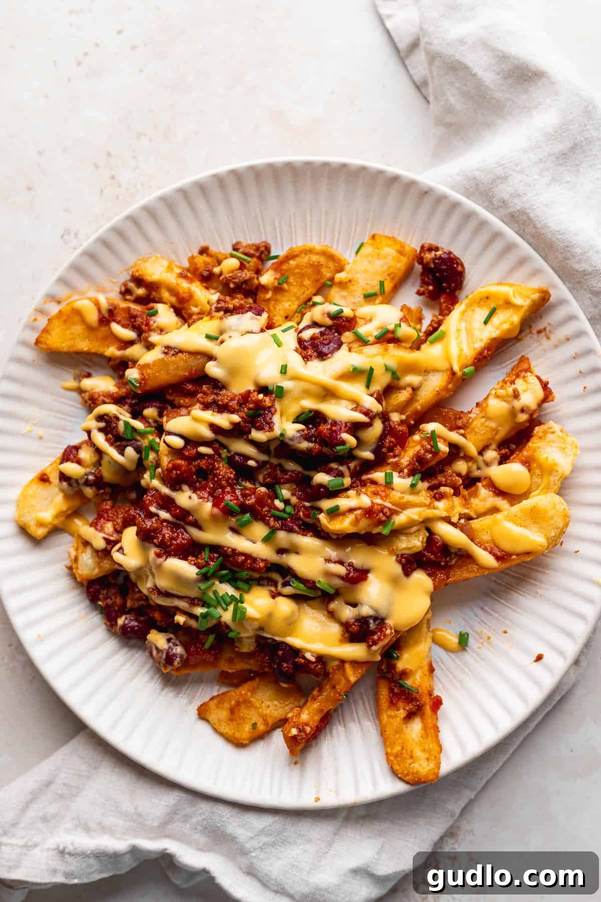 Serving Homemade Chili Cheese Fries A generously loaded plate of chili cheese fries, garnished with fresh herbs.