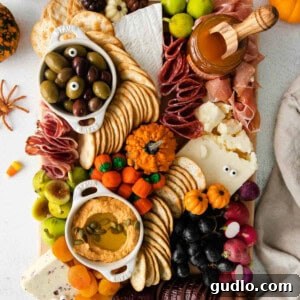 Spiced Pumpkin Pecan Cheese Ball 2 A spooky Halloween themed cheese board with various cheeses, fruits, and crackers.