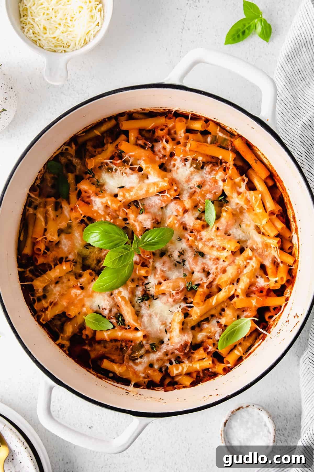 Ultimate Cheesy Ziti Bake 2 A large Dutch oven filled with bubbling baked ziti, garnished with fresh herbs, ready to be served.