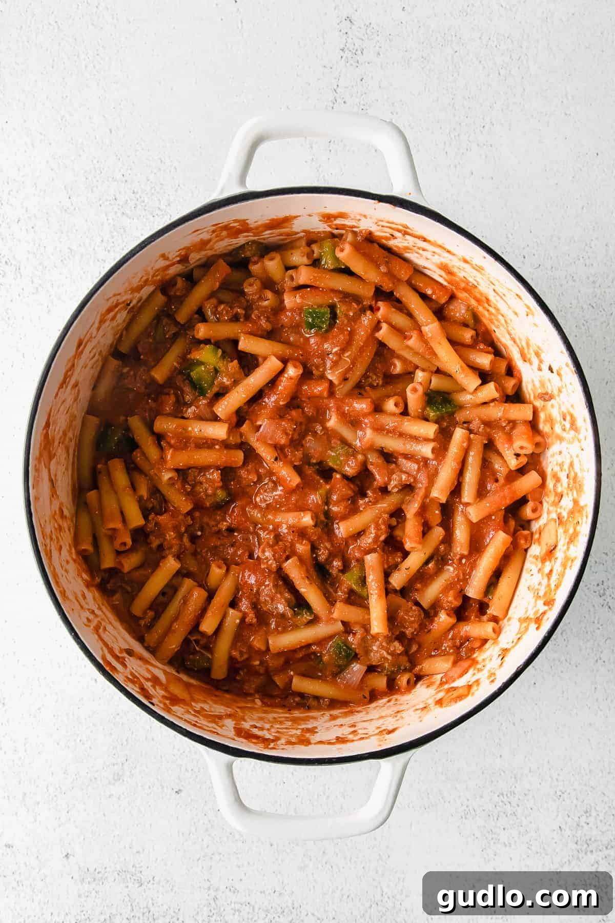 Ultimate Cheesy Ziti Bake 5 A large Dutch oven brimming with perfectly baked ziti, featuring a golden-brown cheesy crust and rich tomato sauce, ready to be served.