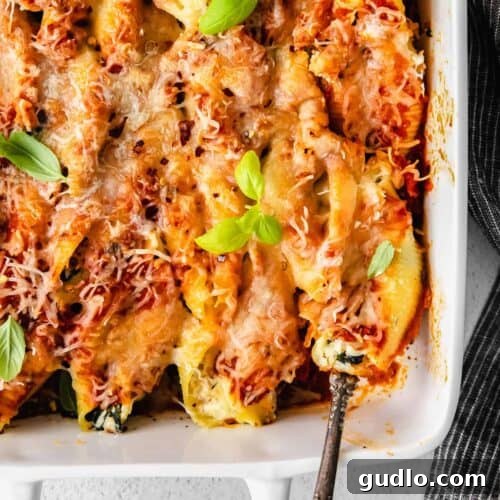 Ricotta stuffed shells garnished with fresh basil leaves in a white baking dish.