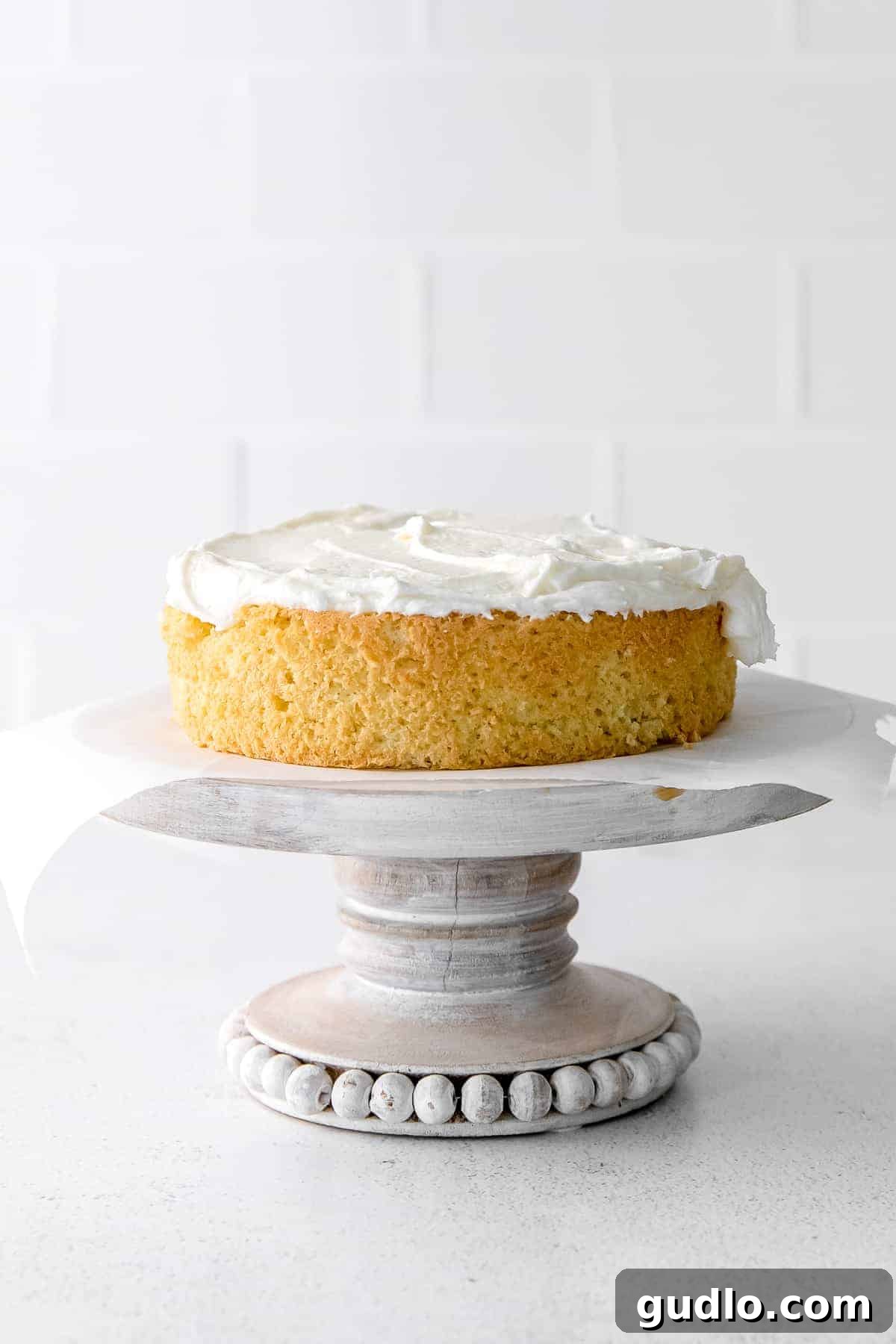 The first layer of Tiramisu Layer Cake, generously covered with creamy mascarpone frosting, ready for the next layer.