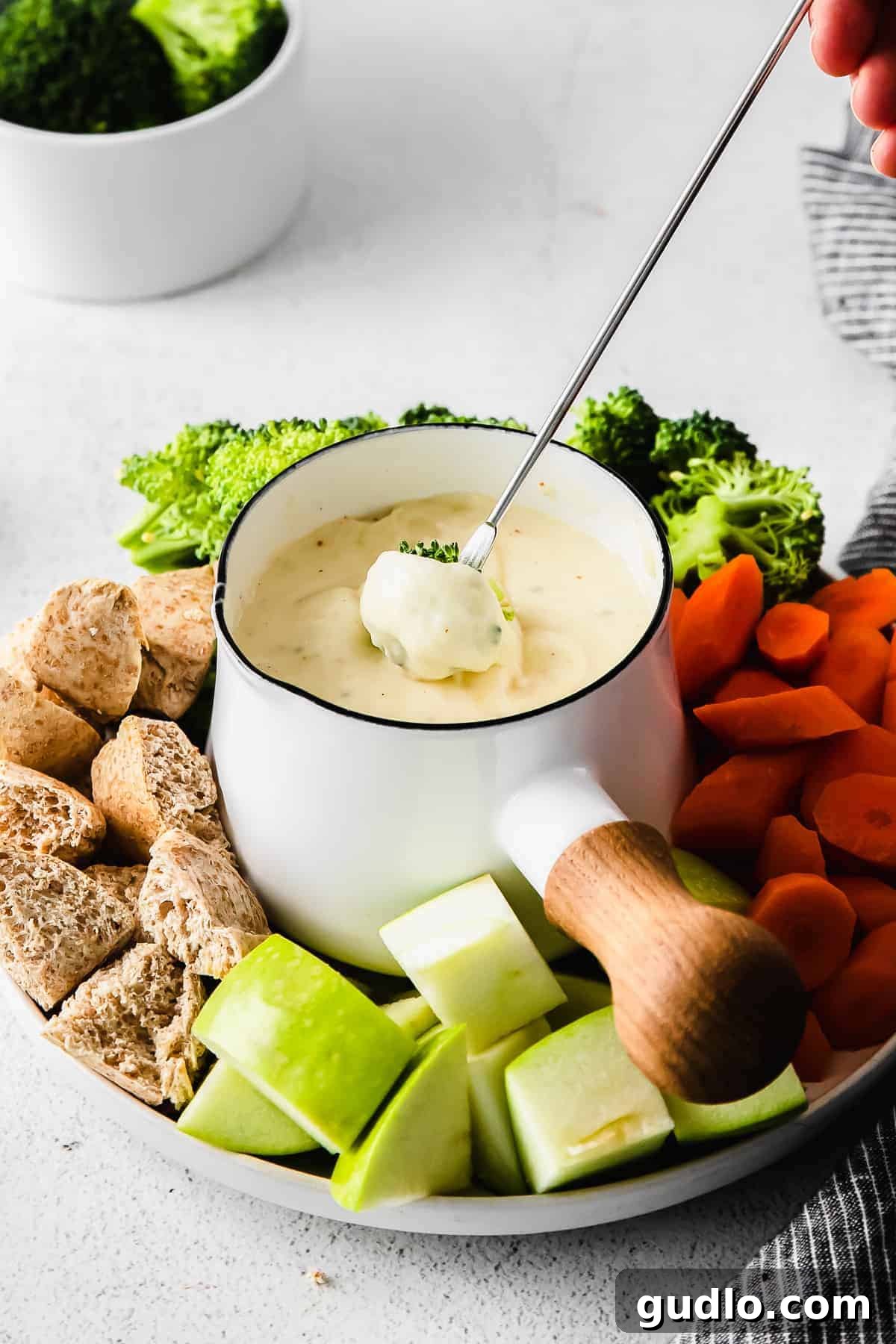 Dipping broccoli into a rich, creamy cheese fondue, highlighting a healthy and delicious fondue dipper.