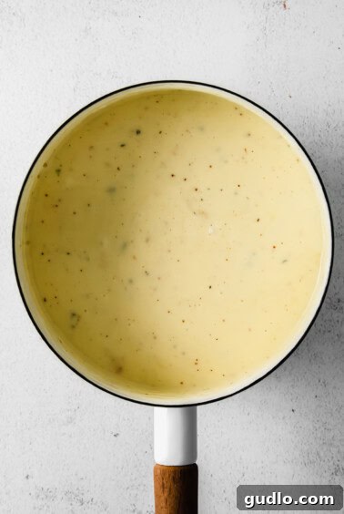 Smooth and creamy cheese fondue simmering gently in a pot, demonstrating perfect consistency.