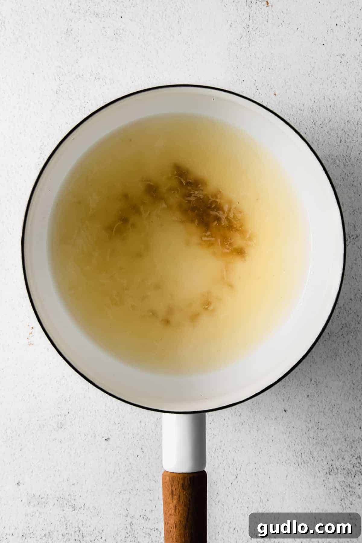 The initial stage of making cheese fondue in a saucepan, showing wine and spices gently heating before cheese is added.