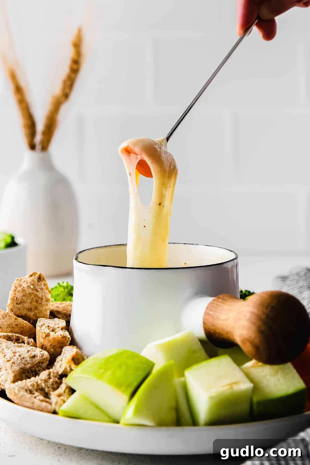 Dipping a fresh carrot stick into a warm, inviting cheese fondue, showcasing a healthy dipper option.