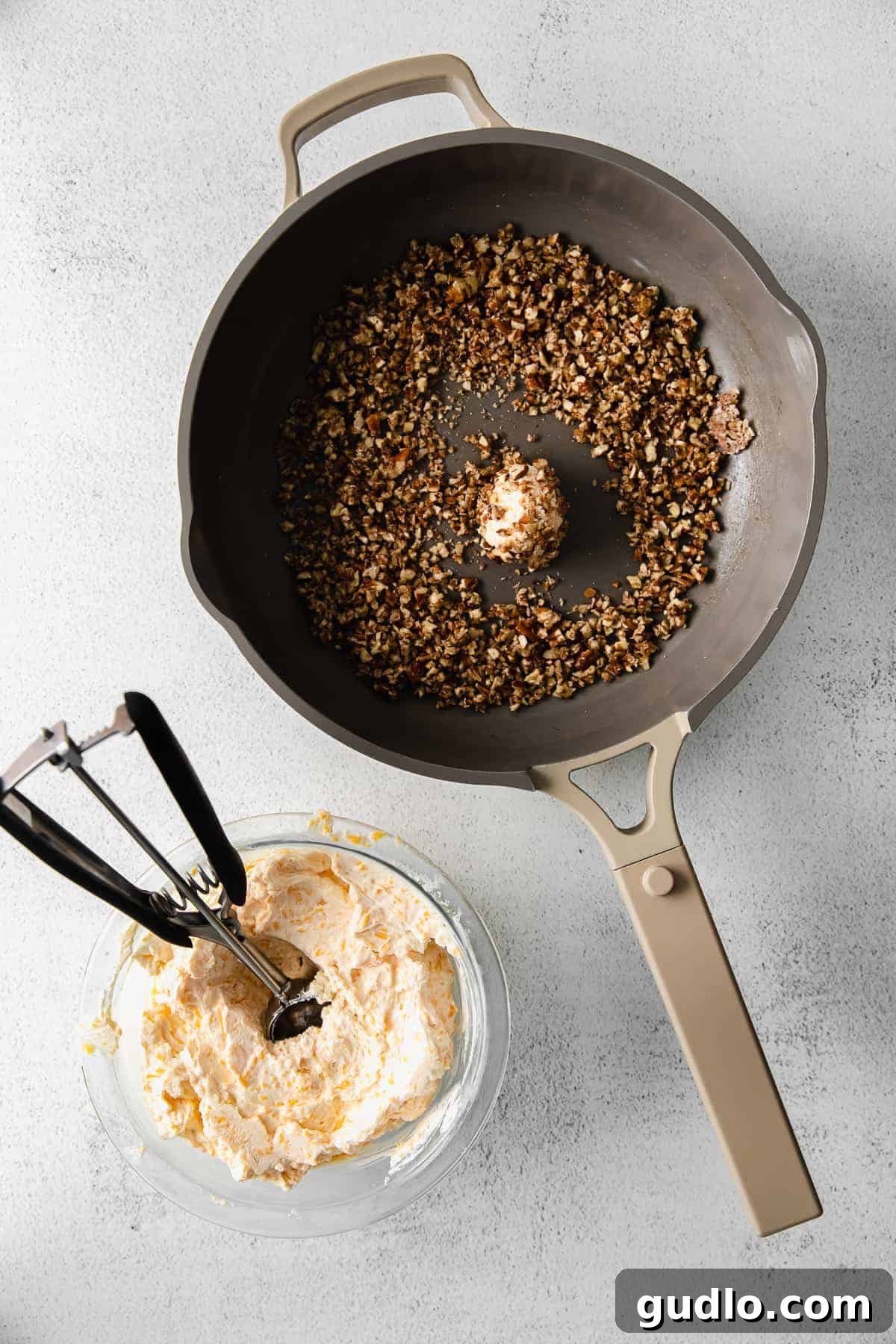 Candied pecans being toasted in a skillet over medium heat