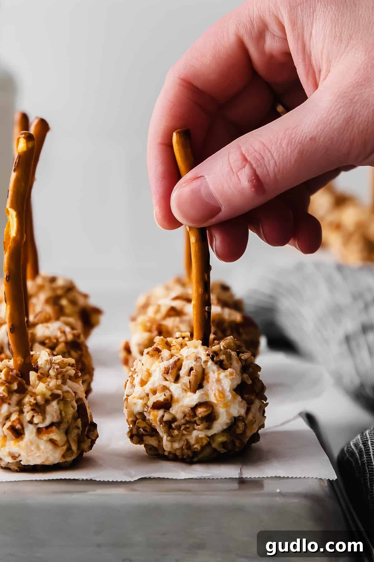 A hand reaching for a cheese ball bite from a platter, ready to enjoy
