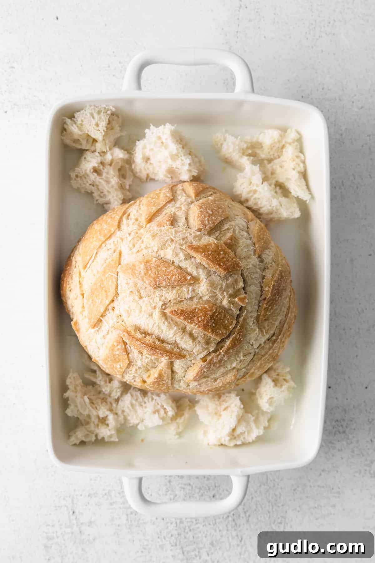 A simple baked brie in bread recipe made with a fresh sourdough loaf. Take your baked brie appetizer up a notch with this pull-apart idea. Sourdough loaf in baking dish