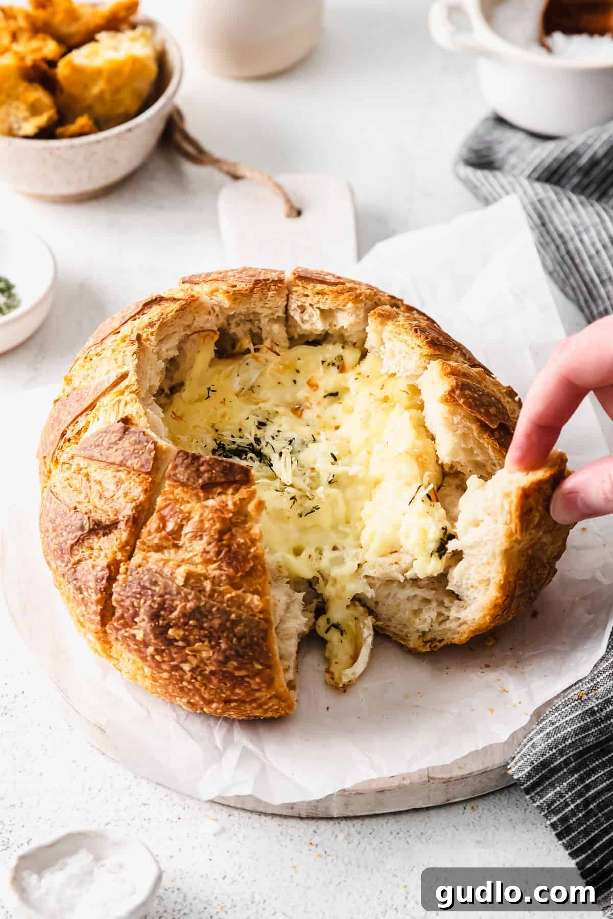 A simple baked brie in bread recipe made with a fresh sourdough loaf. Take your baked brie appetizer up a notch with this pull-apart idea. Pulling apart sourdough