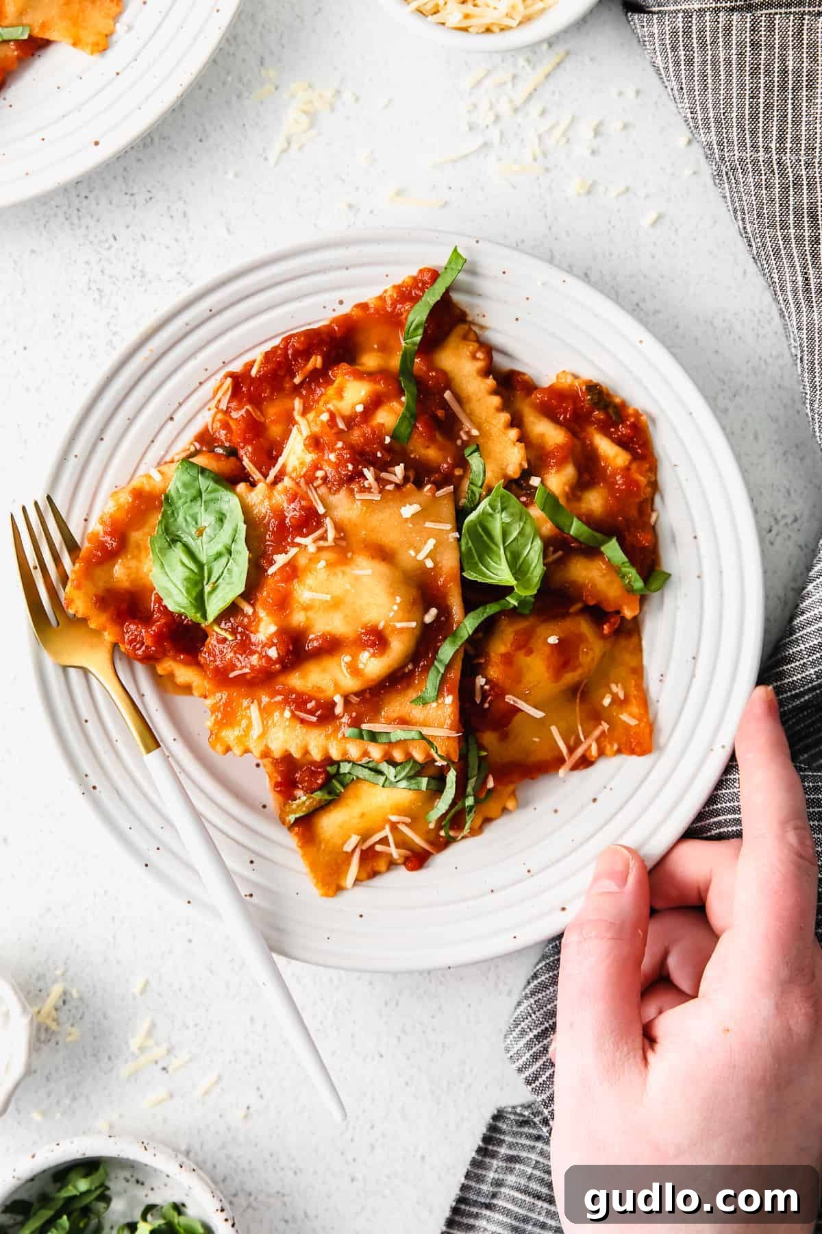 A plate of freshly made homemade cheese ravioli, garnished with herbs.