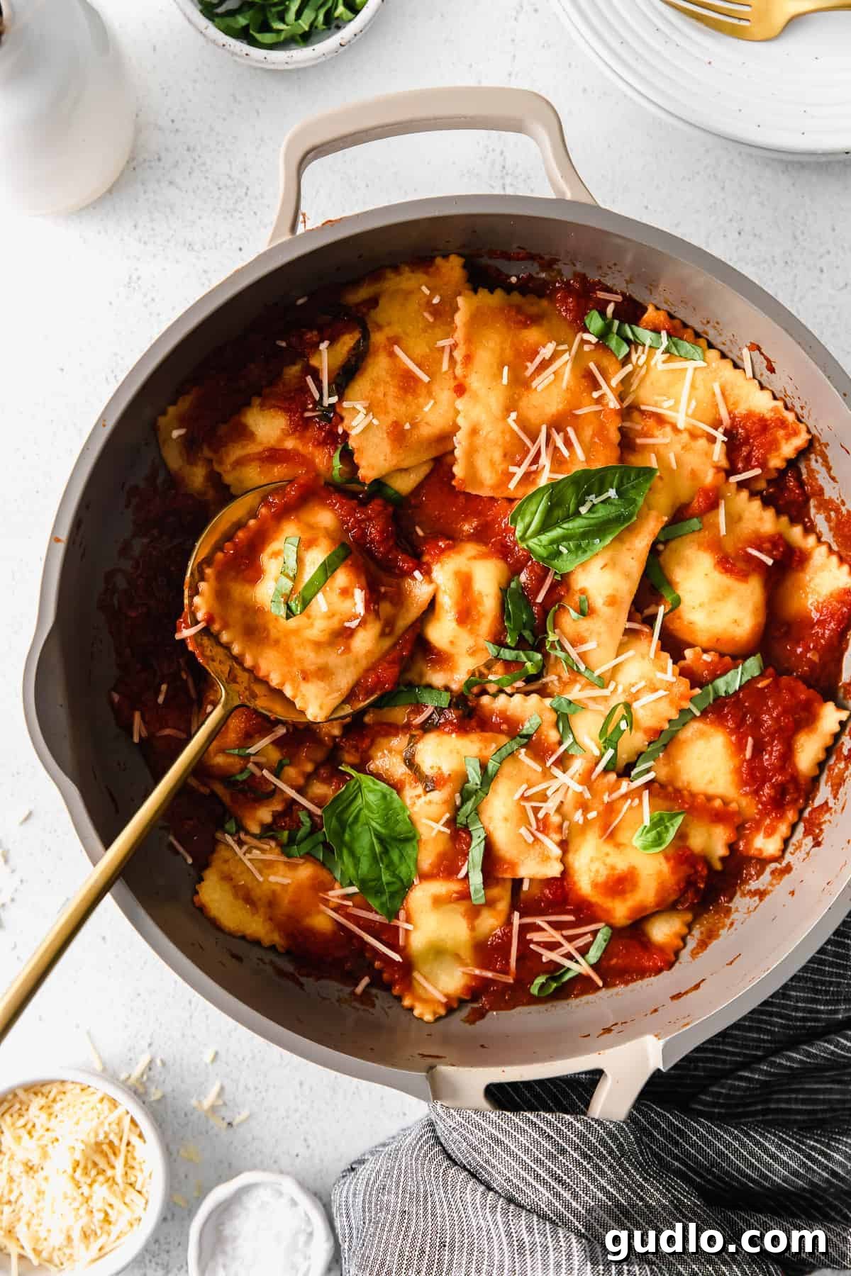 Homemade cheese ravioli served in a skillet with marinara sauce and fresh basil.