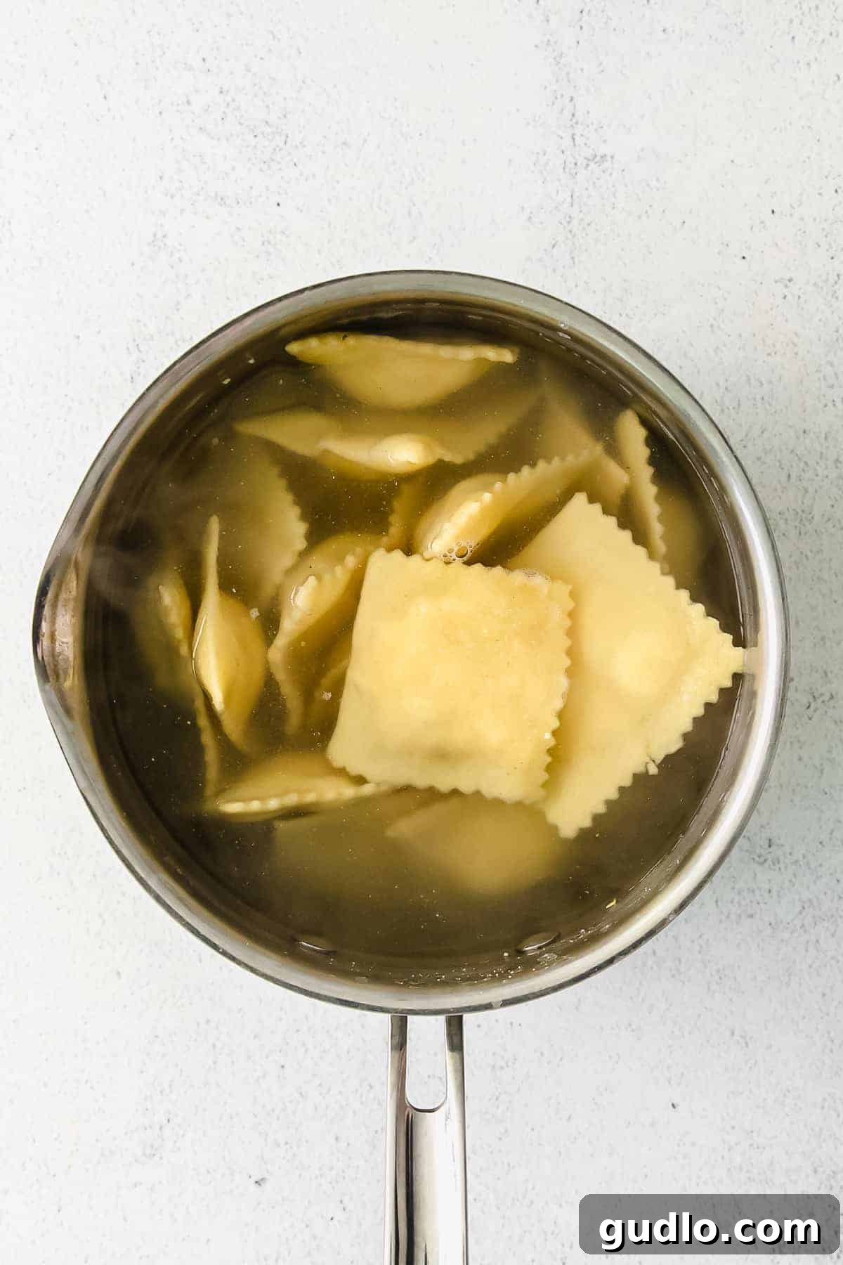 Homemade cheese ravioli cooking in a pot of boiling water.