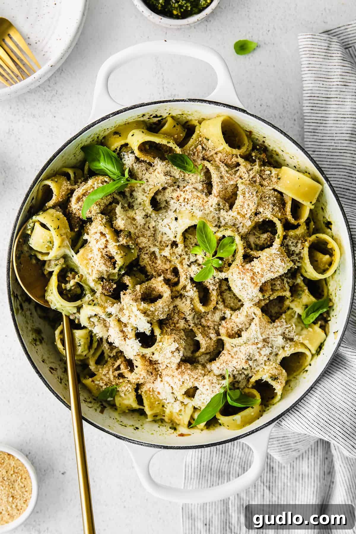 Rich pesto pasta recipe with crumbled Italian sausage in a large Dutch oven, ready to serve.