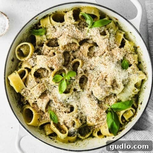 A vibrant bowl of Pesto Pasta with Italian Sausage, garnished with fresh basil.
