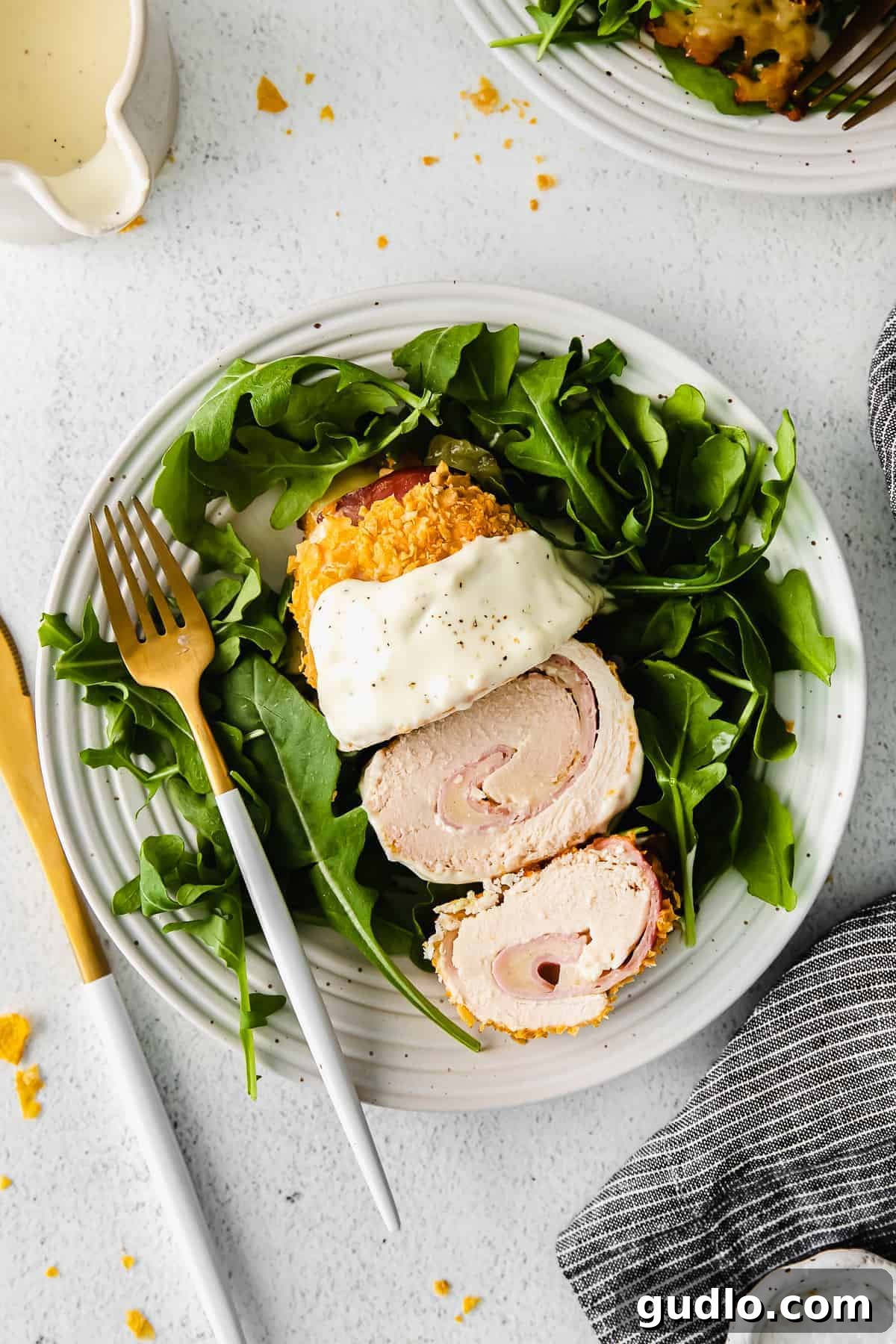 Best Chicken Cordon Bleu Recipe: Flavorful Swiss Cheese Sauce & Crispy Corn Flake Breading chicken cordon bleu on a plate with field greens