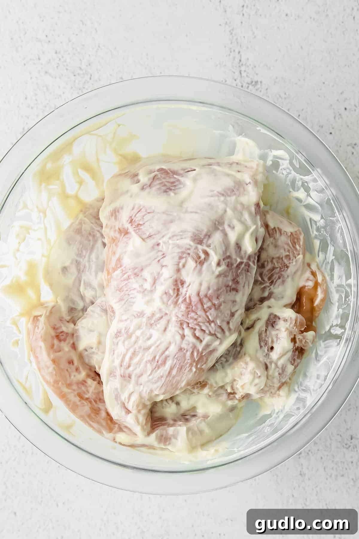 Marinating Chicken for Maximum Flavor and Tenderness raw chicken in a greek yogurt sauce in a bowl