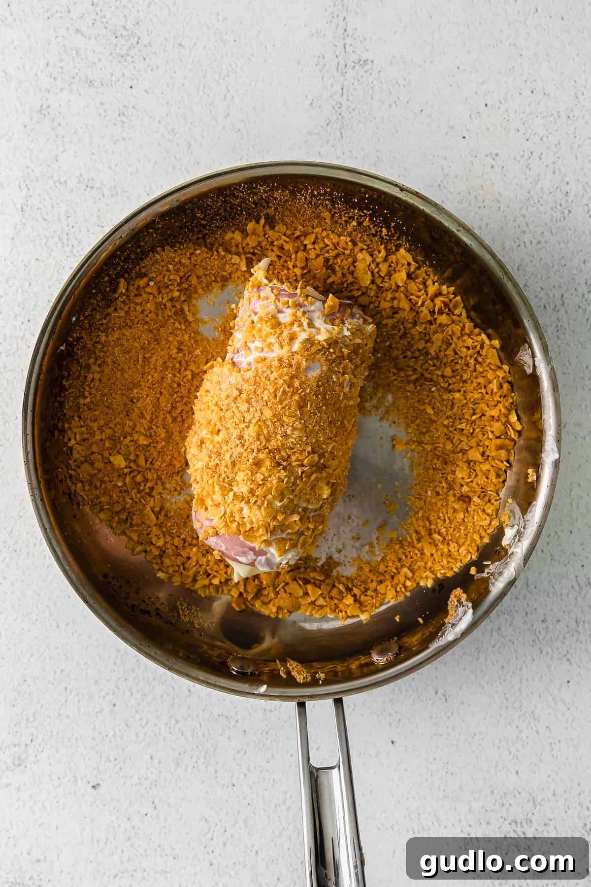 The Secret to a Crispy Corn Flake Breading for Cordon Bleu chicken cordon bleu being rolled in corn flakes for the breading