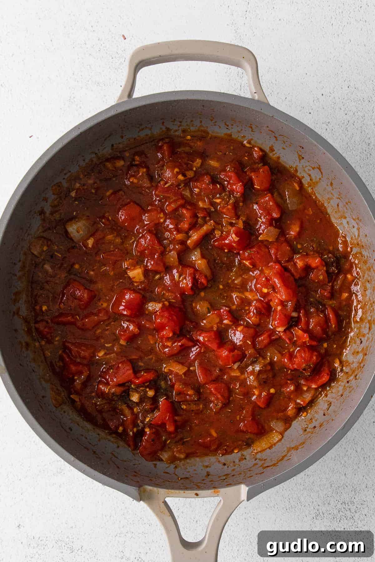 Sautéed Italian sausage, onions, garlic, and diced tomatoes simmering in a pan, forming the rich base of the pepper filling.