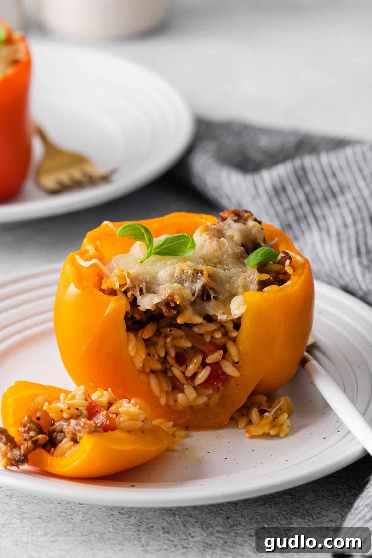 A freshly baked Italian Stuffed Pepper, perfectly cooked and sliced open to reveal the rich, cheesy filling of sausage and orzo.