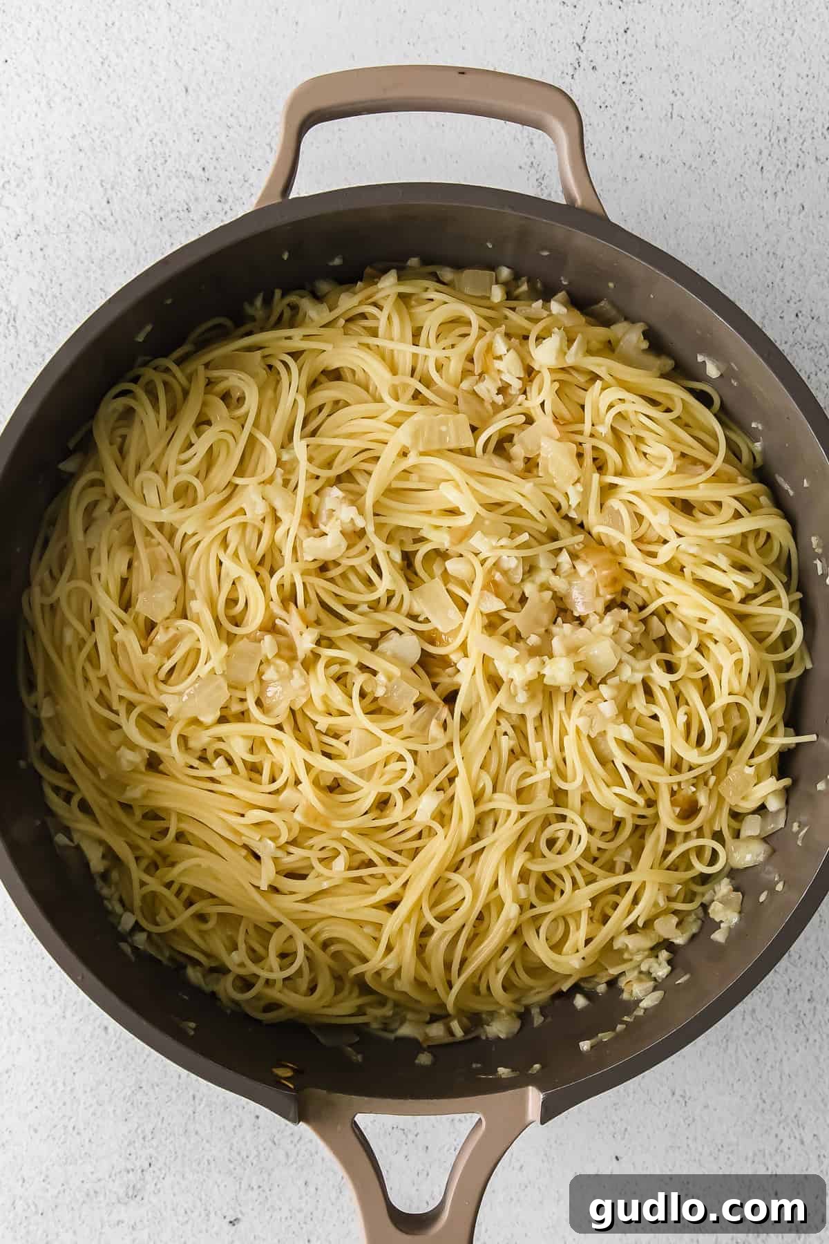 A pan full of cooked pasta mixed with the lemon garlic sauce, ready to be served.