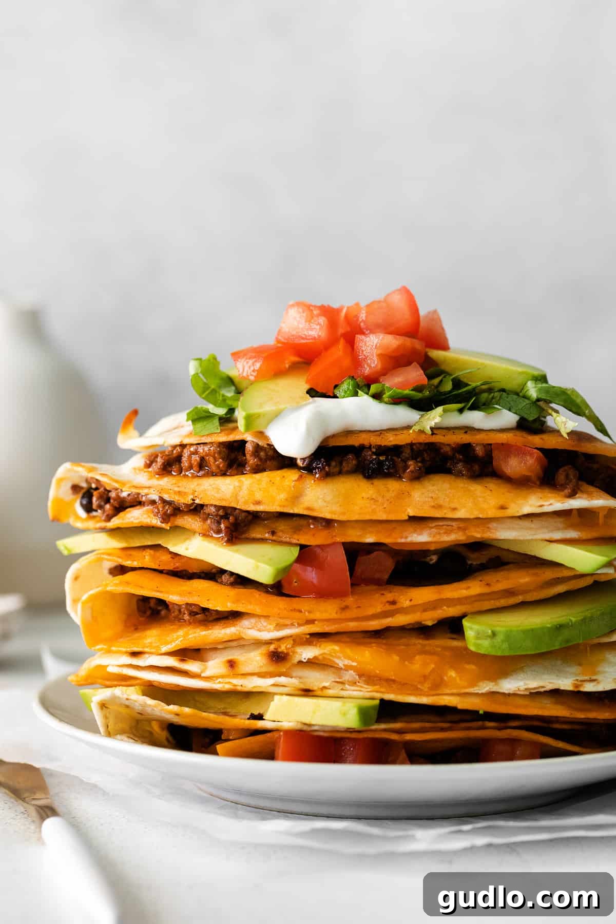 A stack of perfectly cooked ground beef quesadilla triangles, showing the rich filling and golden-brown exterior, artfully arranged on a serving plate.