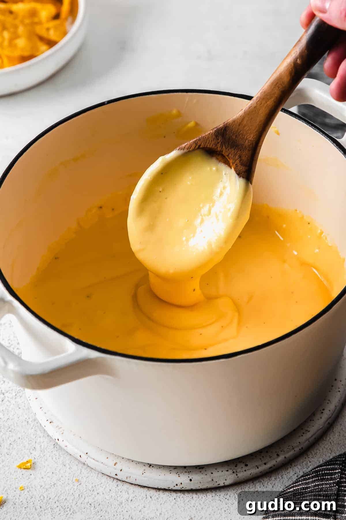 Our Ultimate Velveeta Cheese Sauce is oh so creamy and flavorful and made with easy ingredients. Pair with your favorite pasta, and enjoy! Creamy Velveeta cheese sauce being scooped from a pot with a wooden spoon