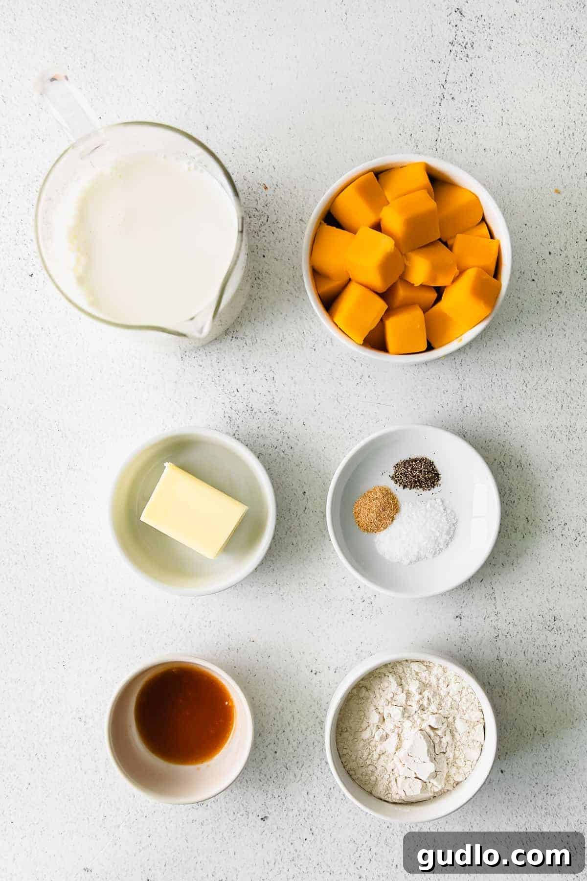 Our Ultimate Velveeta Cheese Sauce is oh so creamy and flavorful and made with easy ingredients. Pair with your favorite pasta, and enjoy! Ingredients for creamy Velveeta cheese sauce laid out on a wooden surface
