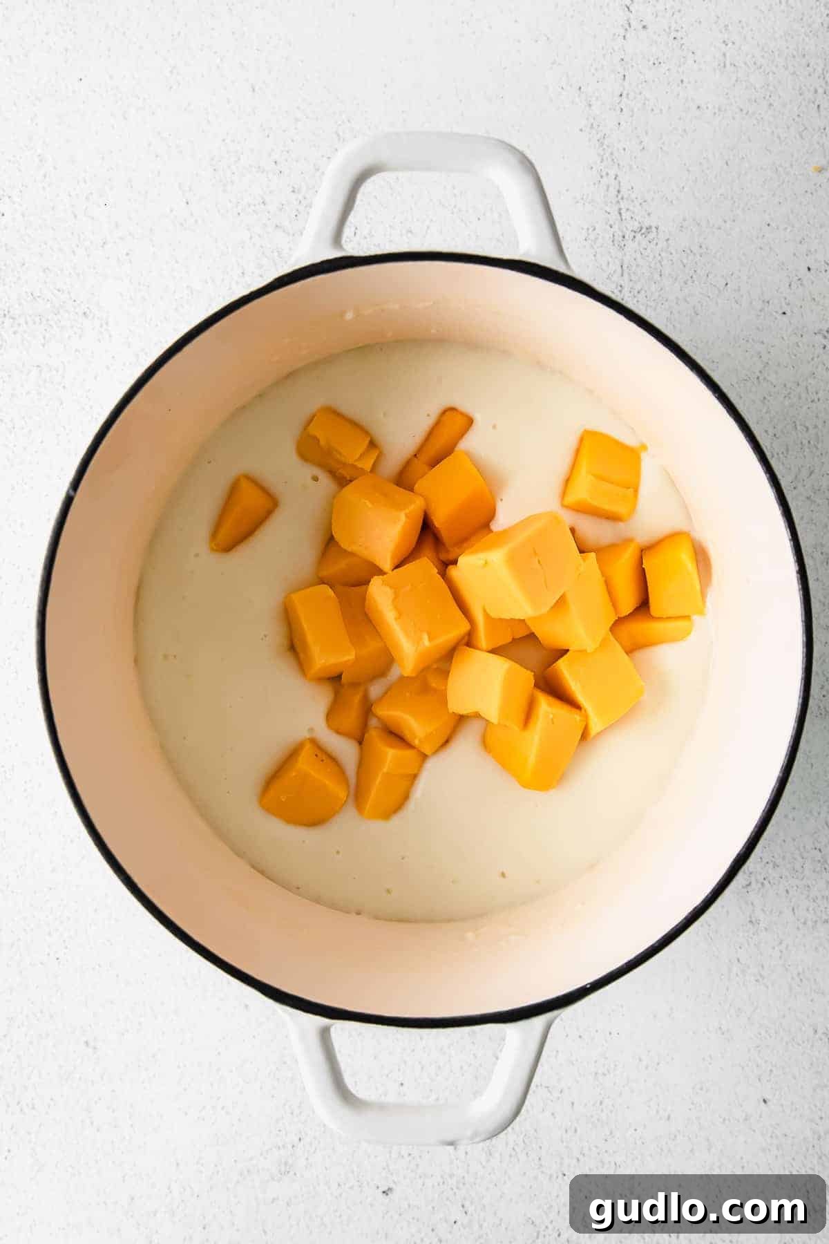 Our Ultimate Velveeta Cheese Sauce is oh so creamy and flavorful and made with easy ingredients. Pair with your favorite pasta, and enjoy! Blocks of Velveeta cheese melting into a golden roux in a stock pot