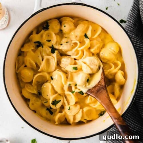 Creamy, velvety Velveeta cheese sauce being stirred with a wooden spoon in a pot.
