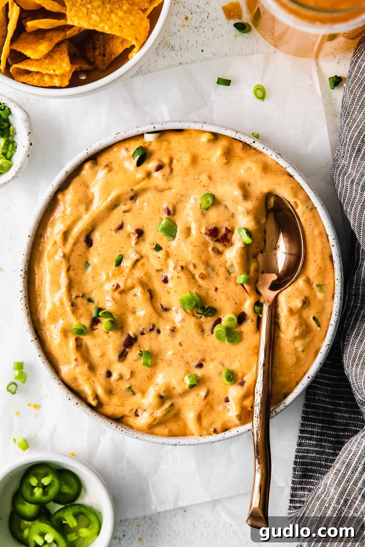 A generous bowl of creamy chili cheese dip with a sturdy serving spoon resting in it, showcasing its rich, inviting texture and warmth, ready to be scooped.