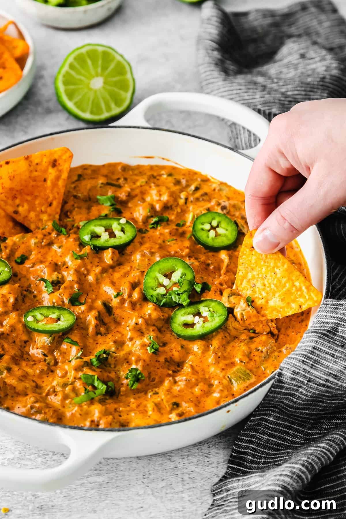Oven-Baked Cheesy Jalapeño Dip 7 A scoop of rich Jalapeño Popper Dip being lifted with a tortilla chip, showcasing its creamy texture and visible jalapeño pieces.