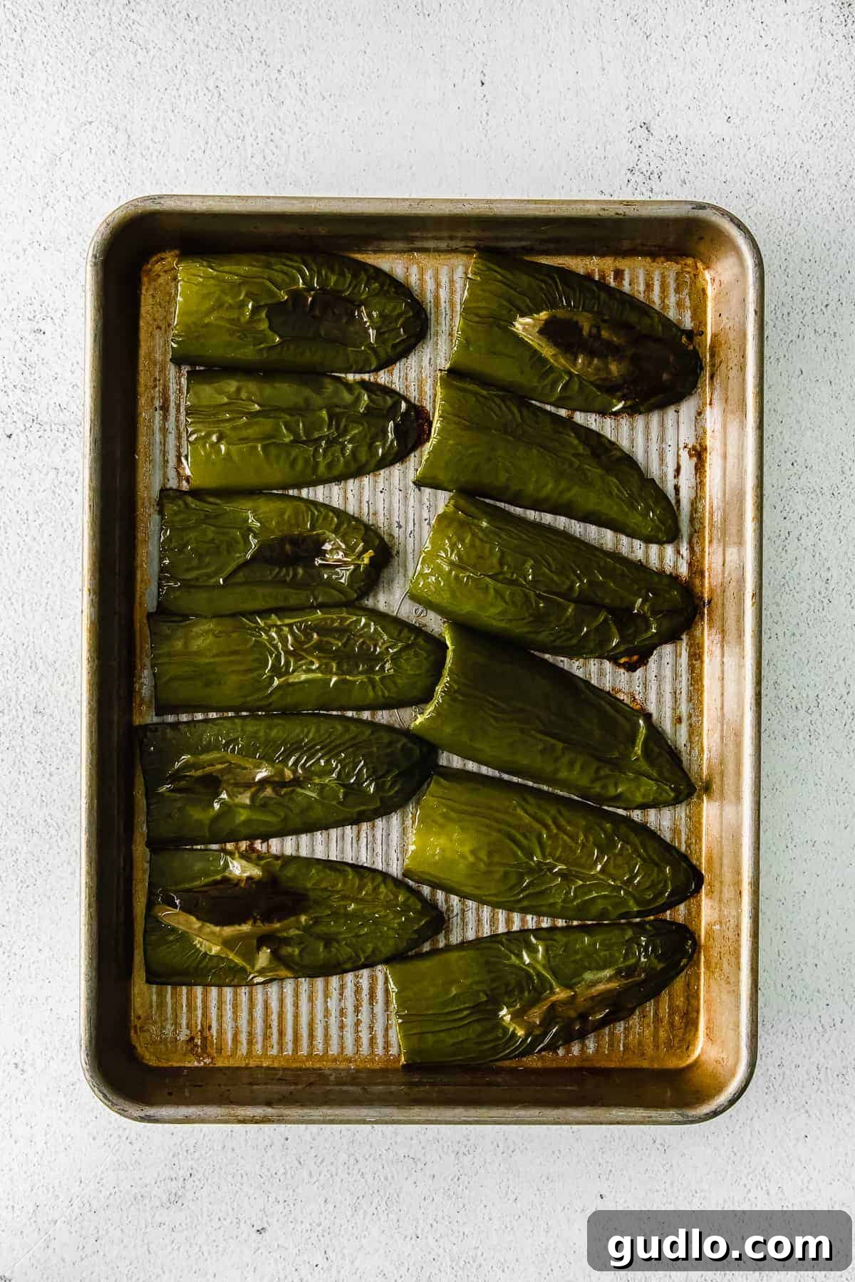 Oven-Baked Cheesy Jalapeño Dip 4 Freshly roasted jalapeños, slightly charred and softened, arranged on a baking sheet after being removed from the oven.