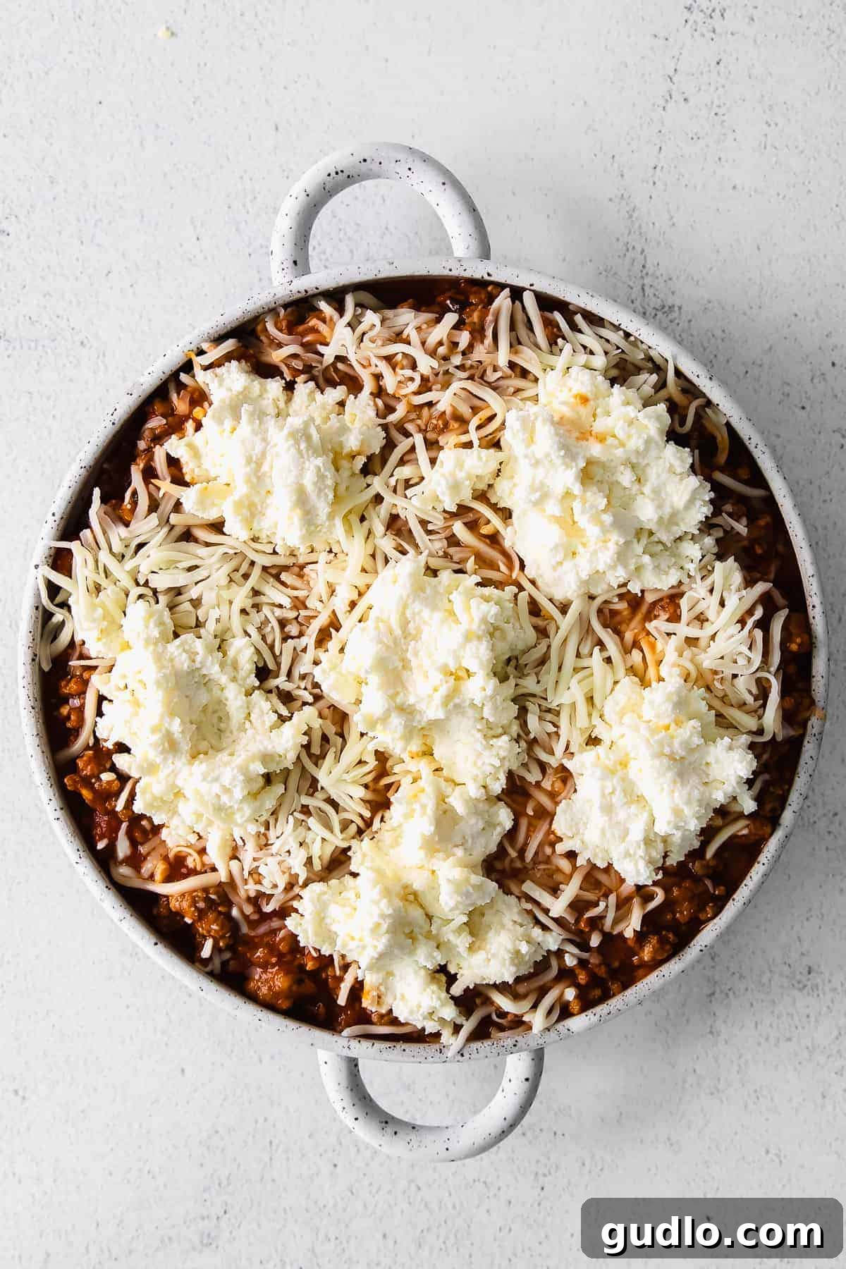 Skillet Lasagna Bake 5 Layers of meat sauce and cheese mixture in a baking dish, topped with mozzarella before baking