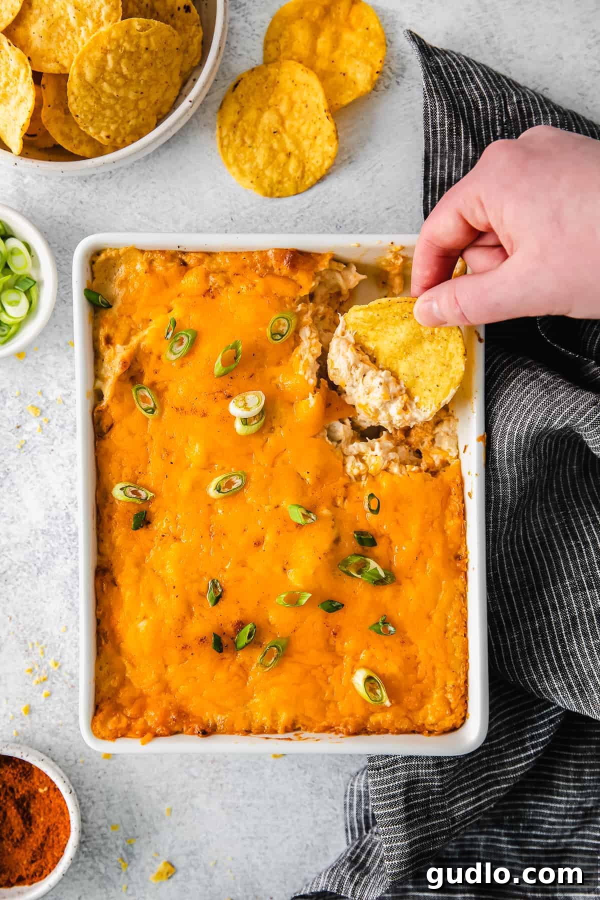 Ultimate Cheesy Crab Dip 2 Scooping generous portions of hot, cheesy crab dip from a baking dish, ready to serve with tortilla chips.