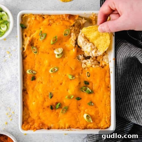 Chip dipping into hot crab dip, showing its cheesy, creamy texture.
