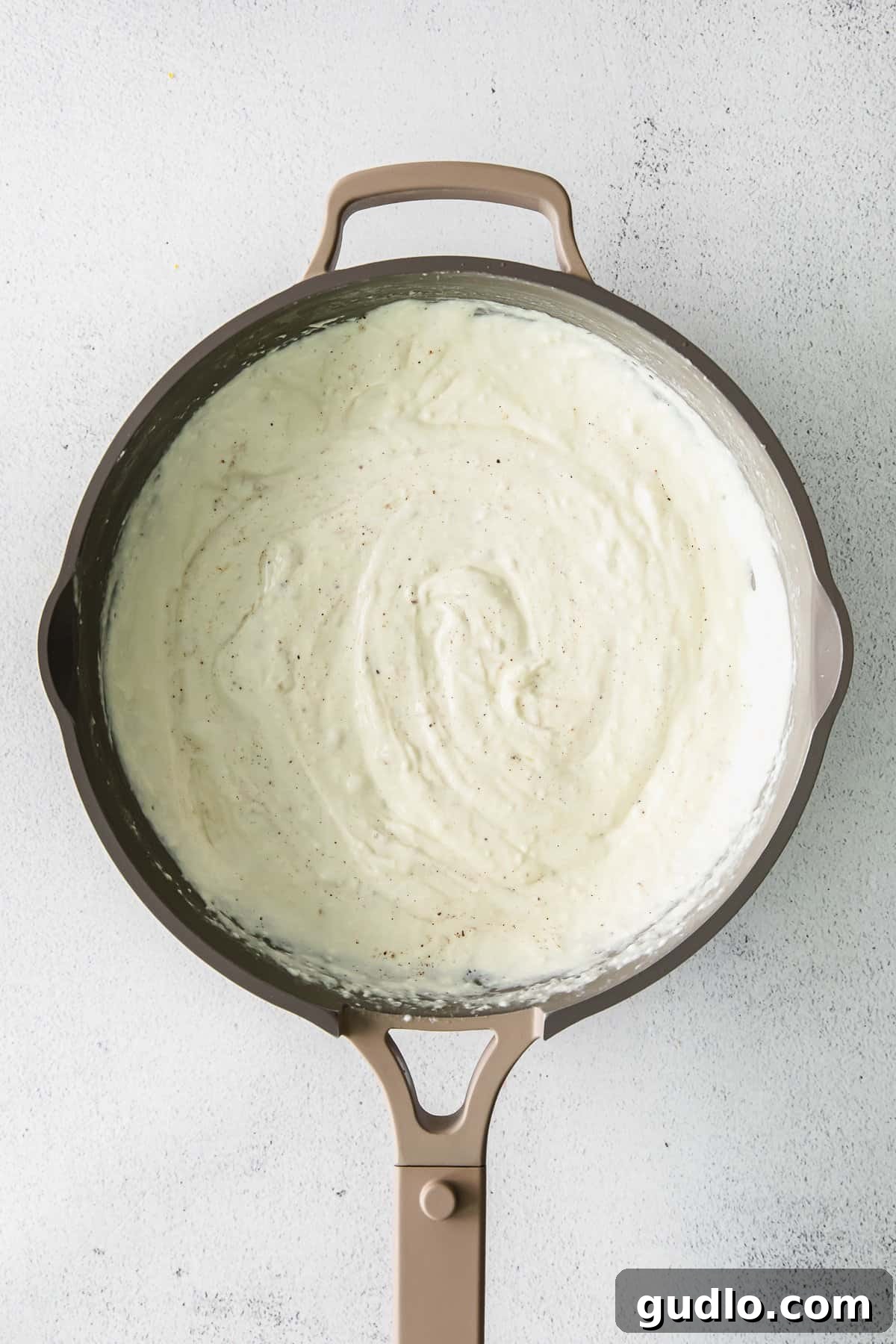 Creamy cream cheese pasta sauce simmering in a skillet.