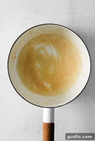 Making a roux by whisking butter and flour in a pot.