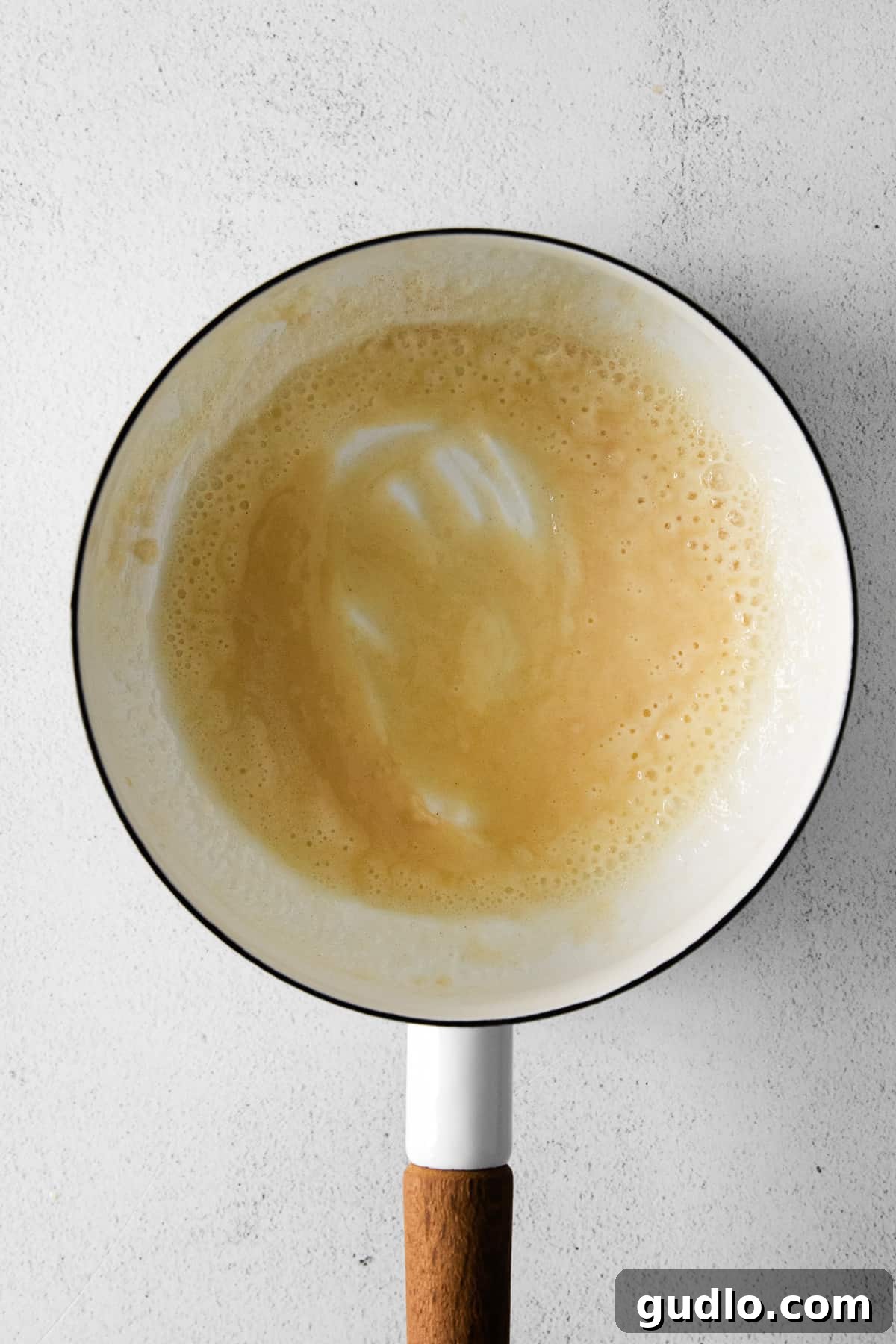 Close-up of butter melting in a skillet, then flour being whisked in to form a smooth roux, the base for the creamy cheese sauce.