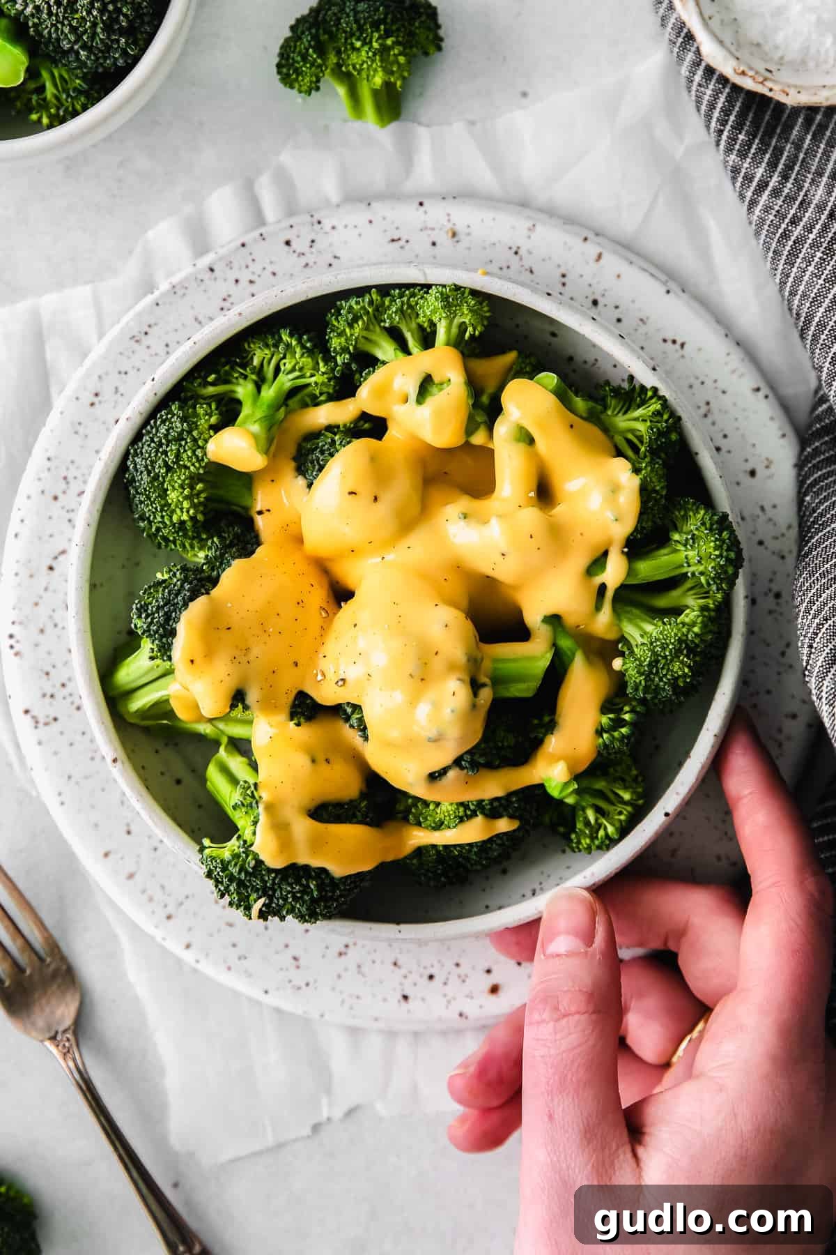 A close-up shot of creamy cheese sauce generously covering steamed broccoli florets.