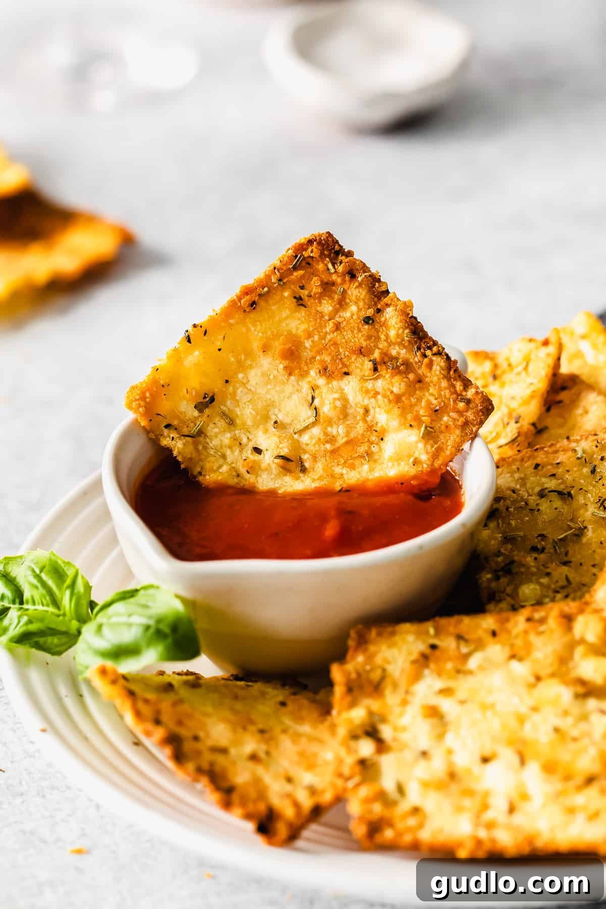 Hand dipping an Air Fryer Pasta Chip into marinara sauce