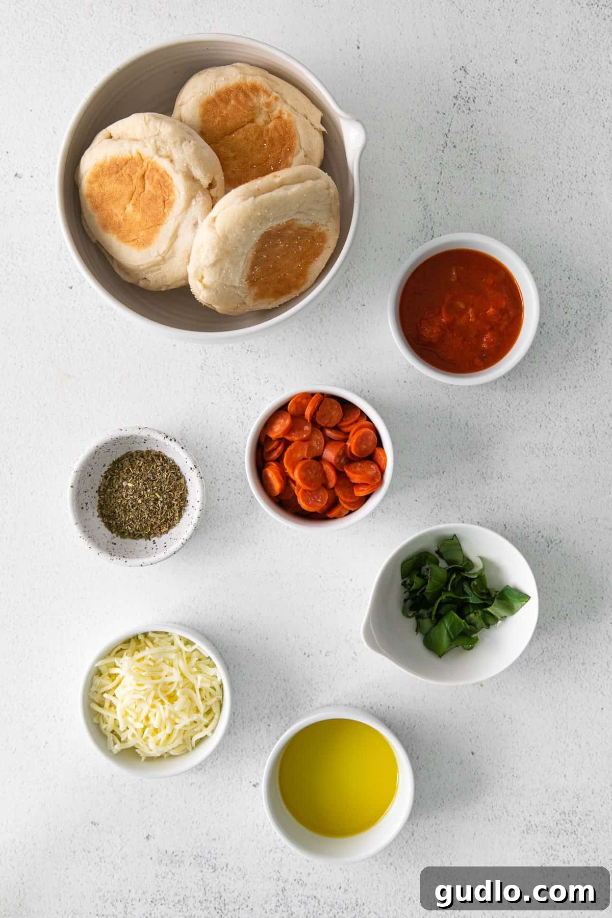 Let dinner be a breeze with English Muffin Pizzas! This kid-friendly dinner idea is made with toasted English muffins and your favorite pizza toppings. A selection of fresh ingredients including English muffins, marinara sauce, cheese, and pepperoni laid out on a countertop, ready for making pizza.